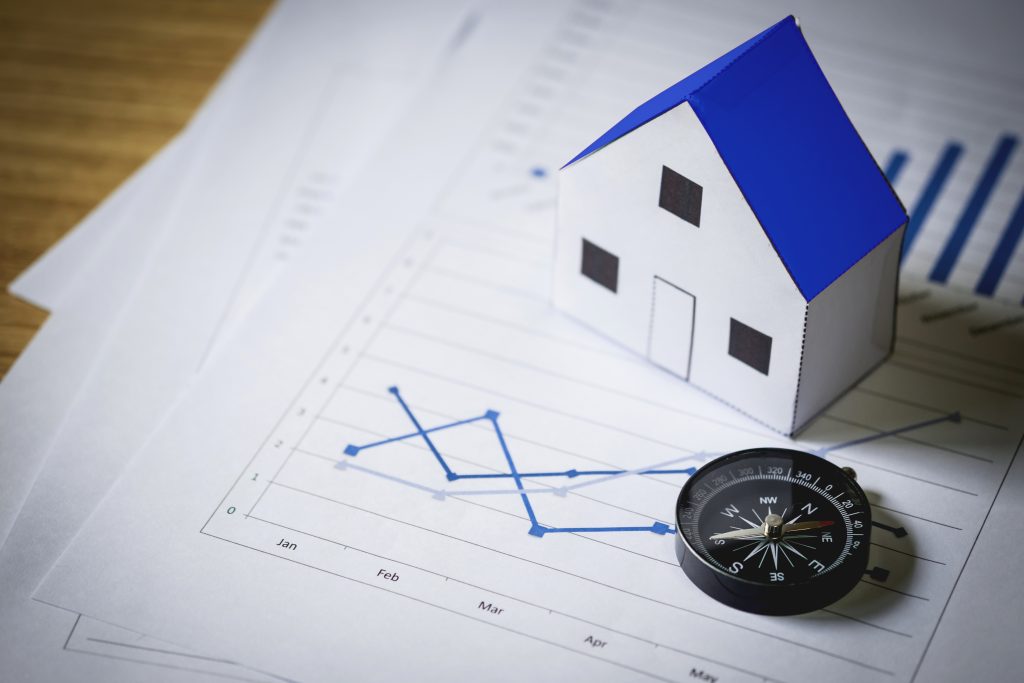 house model and compass on plan background, real estate concept